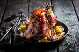 Tasty grilled pheasant with bacon, spices and vegetables on burned table